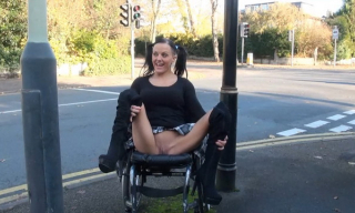 Wheelchair-bound Brit Leah Caprice flashes by the busy road parting booted legs